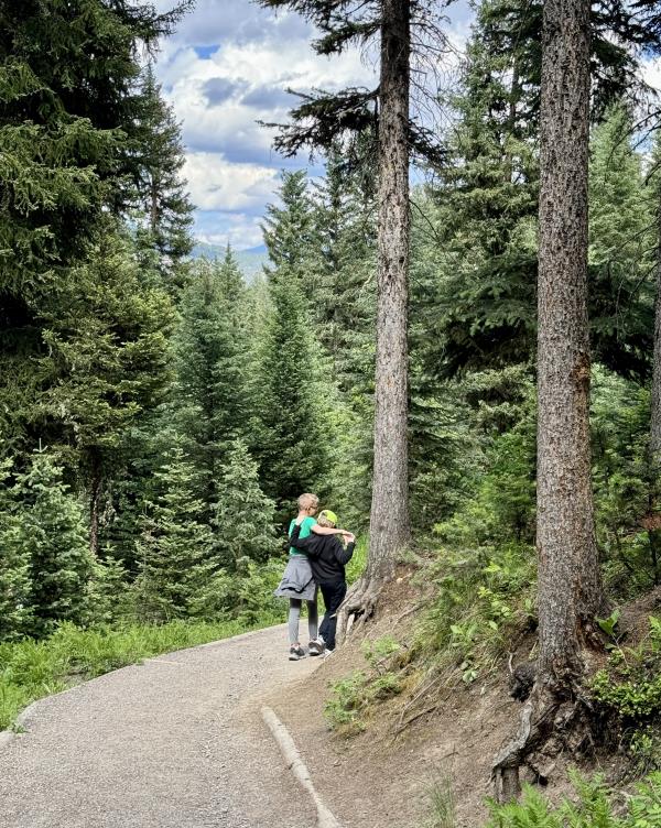 Image of two boys with their arms around one another on a hiking trail