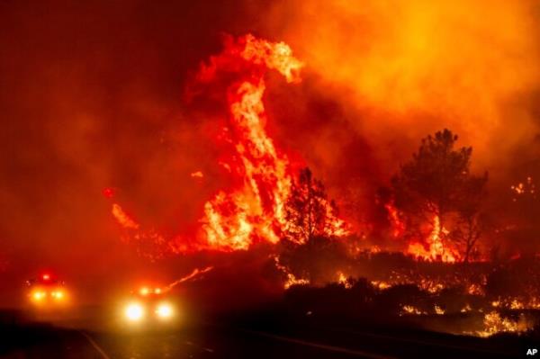Flames leap above fire vehicles as the Park Fire jumps Highway 36 near Paynes Creek in Tehama County, California, July 26, 2024.