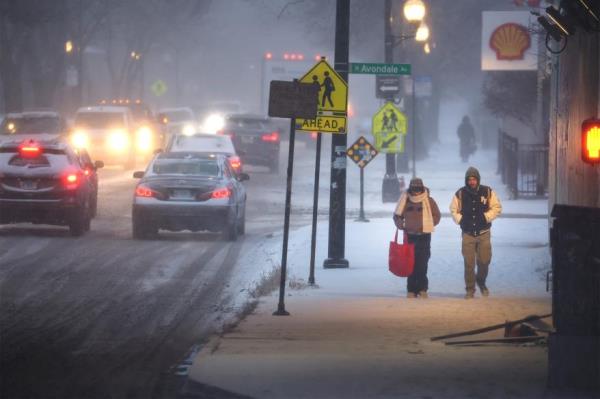 Pedestrians navigate a snow-covered sidewalk as temperatures hang in the single-digits on Dec. 22, 2022 in Chicago.