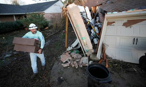 A resident carries some of his belo<em></em>ngings out of his storm-damaged home on Jan. 24, 2023, in Pasadena, Texas. 