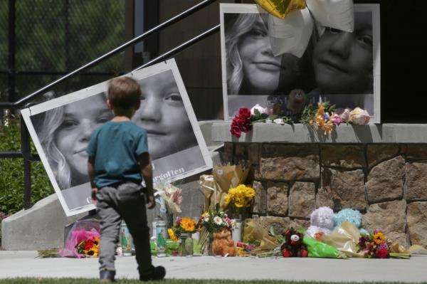 A boy looks at a memorial for Tylee Ryan and Joshua 