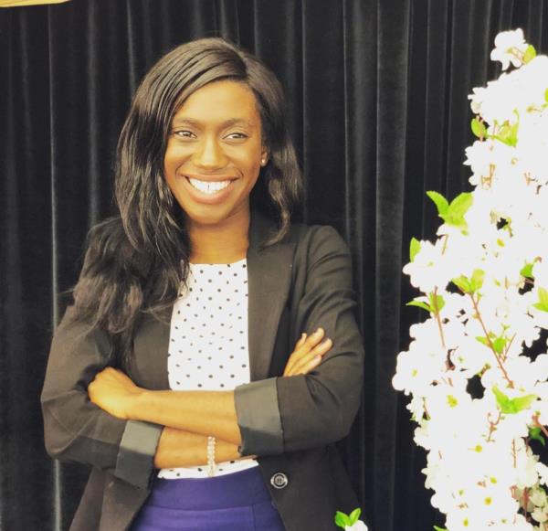 Eunice Dwumfour smiling with her arms crossed in a black blazer.