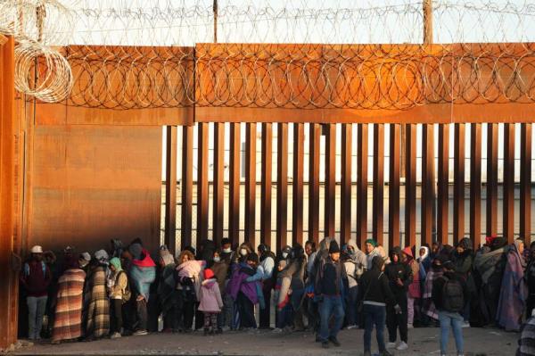 Migrants who crossed the U.S.-Mexico border wait to be transported by U.S. Customs and Border Protection officers.