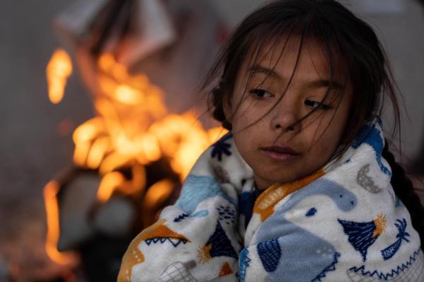 Blaidimar, 8, from Venezuela warms up by a fire outside the U.S.-Mexico border fence while waiting to make asylum claims in El Paso, Texas on Dec. 21.