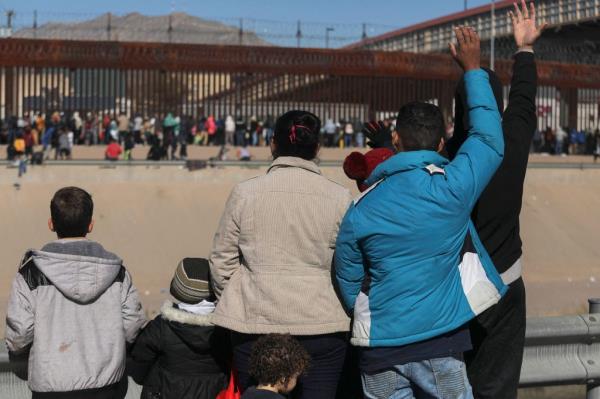 Venezuelan migrants watch others line up at the border wall to be received by Border Patrol agents after crossing the Rio Grande river into the U.S. on Dec. 21.