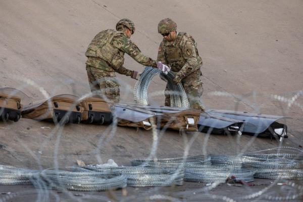 Texas Natio<em></em>nal Guard troops unroll coils of co<em></em>ncertina wire near the U.S.-Mexico border on December 21, 2022 as 