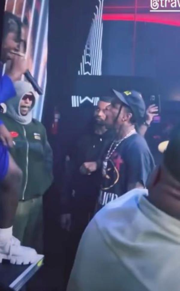 Travis Scott looks up at person performing on stage