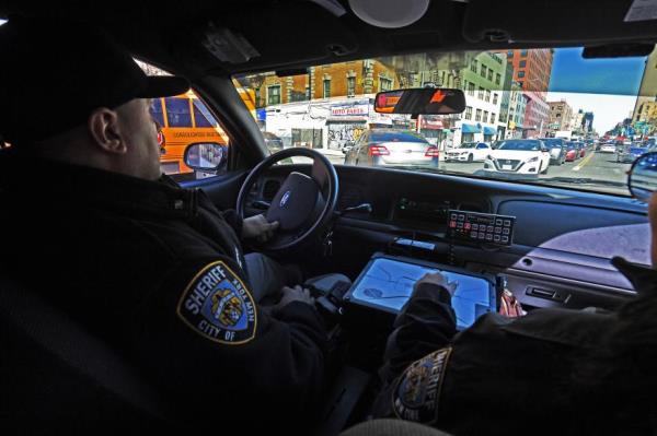 Police drive in a cruiser on the way to raid illegal smoke shops in Washington Heights.