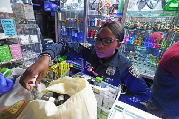 An officer rifles through one of the shop's inventory.