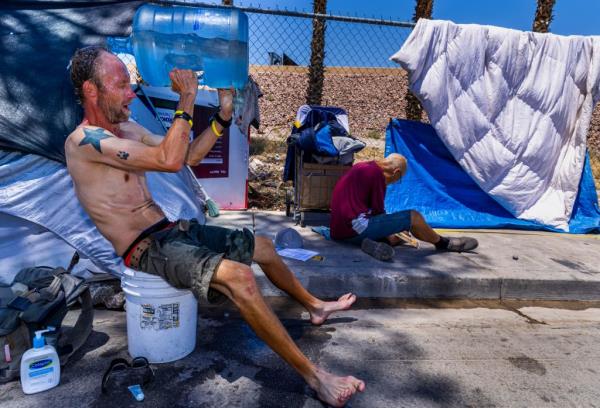 Milton John Scott III pouring water over his head from a jug to cool down in the excessive heat at his shelter in Las Vegas