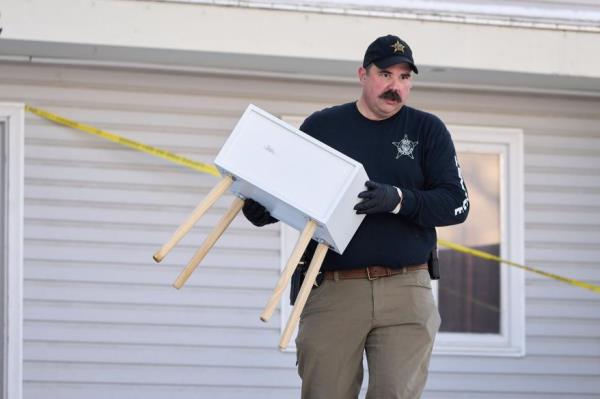 A police officer carrying furniture out of the house.