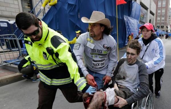 Emergency Medical Services EMT Paul Mitchell, left, Carlos Arredondo, center, and Devin Wang, rear, push Jeff Bauman in a wheelchair after he was injured in one of two explosions near the finish line of the Boston Marathon 