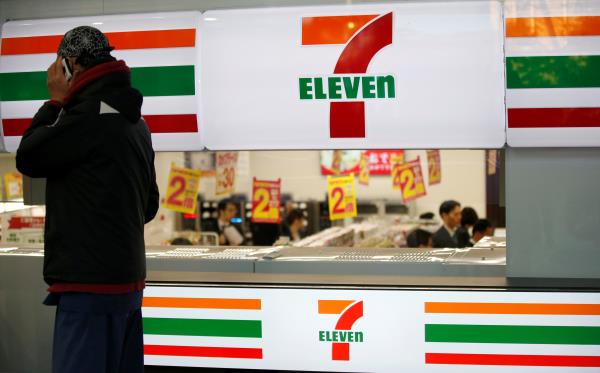 A man uses a mobile phone outside a 7-Eleven co<em></em>nvenience store in Tokyo