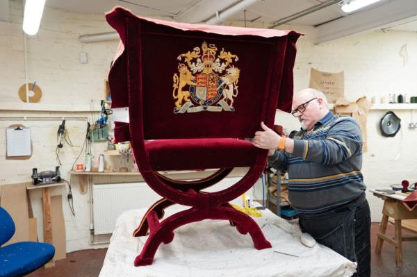 Upholsterer Alex Burnett works on one of the throne chairs.