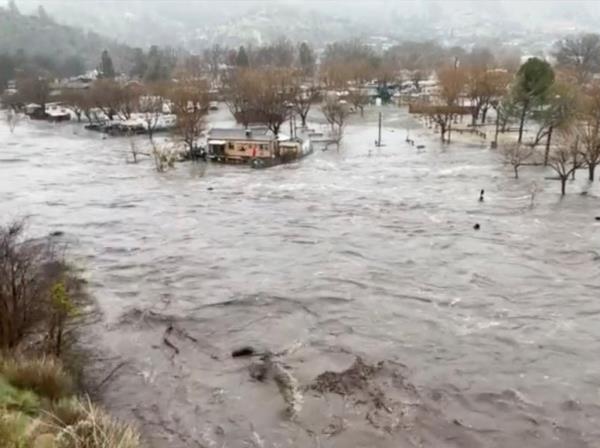 A man walks through floodwaters on College Road in Watsonville, Calif., Friday, March 10, 2023.