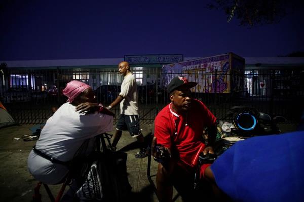 Homeless persons sit along 16th Street in the East Village area of Downtown San Diego on Sept. 26, 2017.