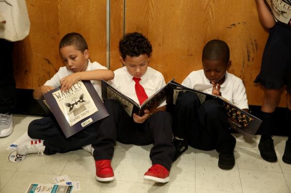 Young kids in ties sitting on the floor reading