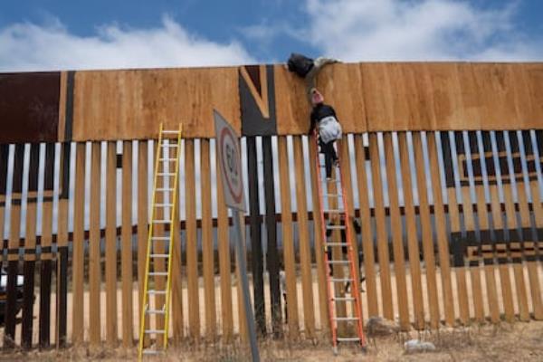 Dos migrantes saltan el muro fro<em></em>nterizo entre Tijuana y San Diego en junio de 2024.