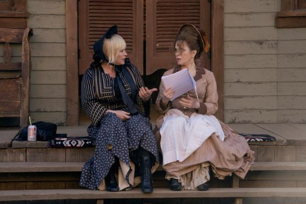 Patricia Arquette wearing a bo<em></em>nnet sitting on wooden steps. 
