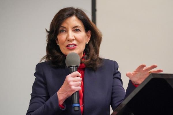Gov. Kathy Hochul holds microphone with her right hand as she speaks at a podium