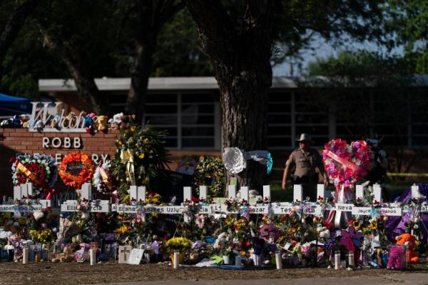Flowers and candles are placed around crosses.