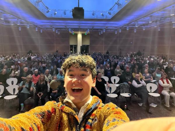 Rajbhandari posing in front of a room full of people.