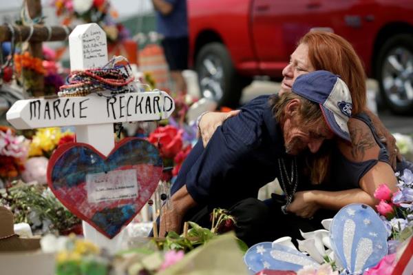 Anto<em></em>nio Basco, whose wife Margie Reckard was murdered during a shooting at a Walmart store, is comforted by a woman next to a white wooden cross bearing the name of his late wife, at a memorial for the victims.