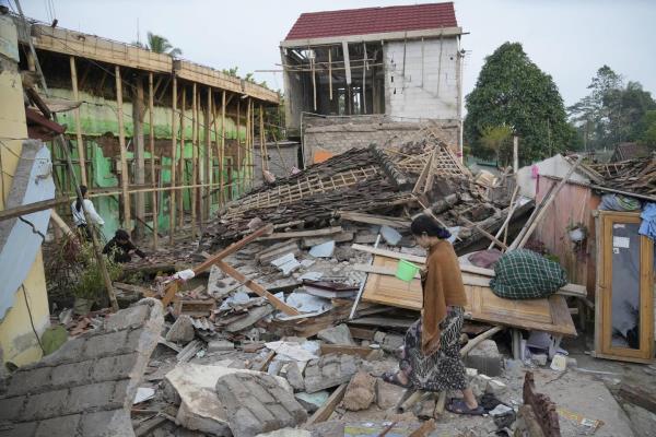 A woman walks past the ruins of buildings flattened by Monday's earthquake in Cianjur, West Java, Indo<em></em>nesia Tuesday, Nov. 22, 2022. 