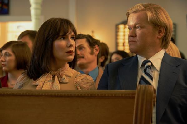 Lily Rabe and Jesse Plemons sitting in a church pew, looking at each other. 