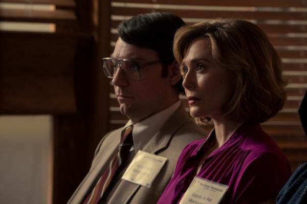 Patrick Fugit and Elizabeth Olsen sitting next to each other looking serious in an office. 