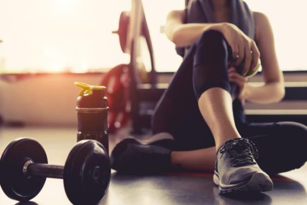 woman sitting in gym with weight and water bottle