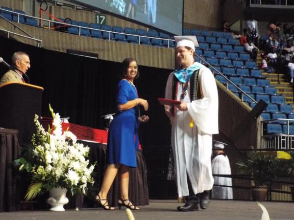 a student is pictured with his diploma at graduation