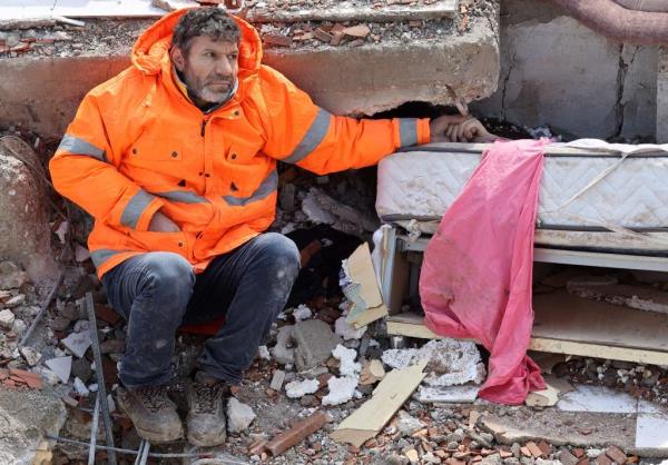 Mesut Hancer holds the hand of his 15-year-old daughter Irmak, who died in the earthquake in Kahramanmaras, Turkey, close to the quake's epicenter.