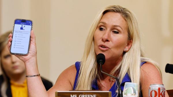 Marjorie Taylor Greene holds up phone with app