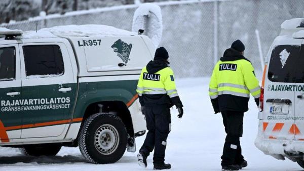 Customs officials walk between Finnish Border Guard vehicles at the Raja-Jooseppi internatio<em></em>nal border crossing station