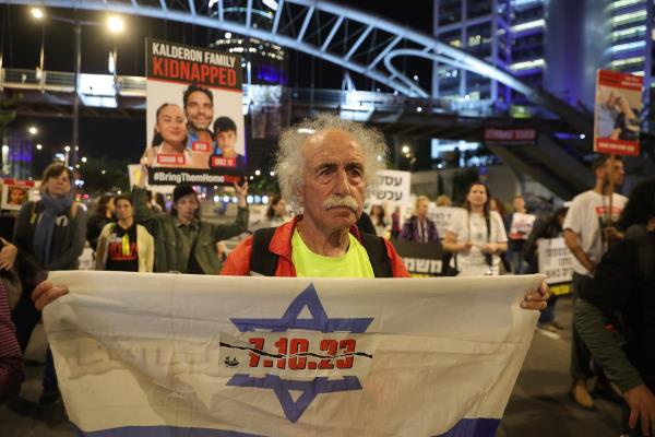 An elderly man holds up a banner saying: 7.10.23 at a demo<em></em>nstration by the families of hostages in Tel Aviv, December 2023