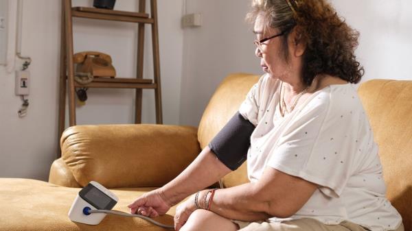 Woman in a white t-shirt wearing a blood pressure cuff.